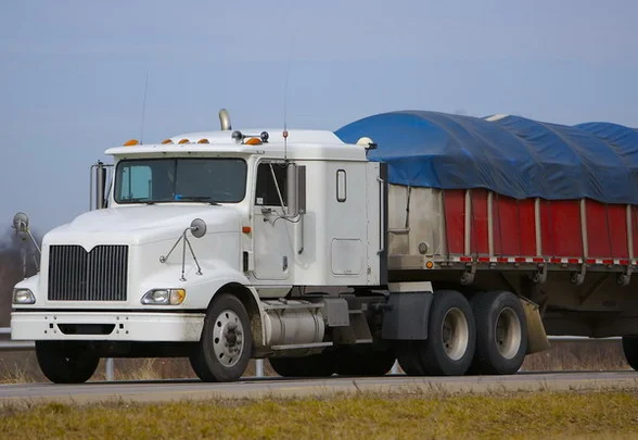 Semi truck with trailer tarp system for hauling grain and materials